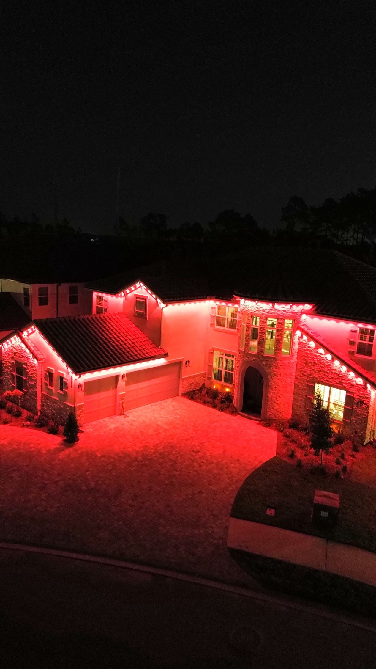 Aerial view of a home with red permanent color-changing roofline lighting