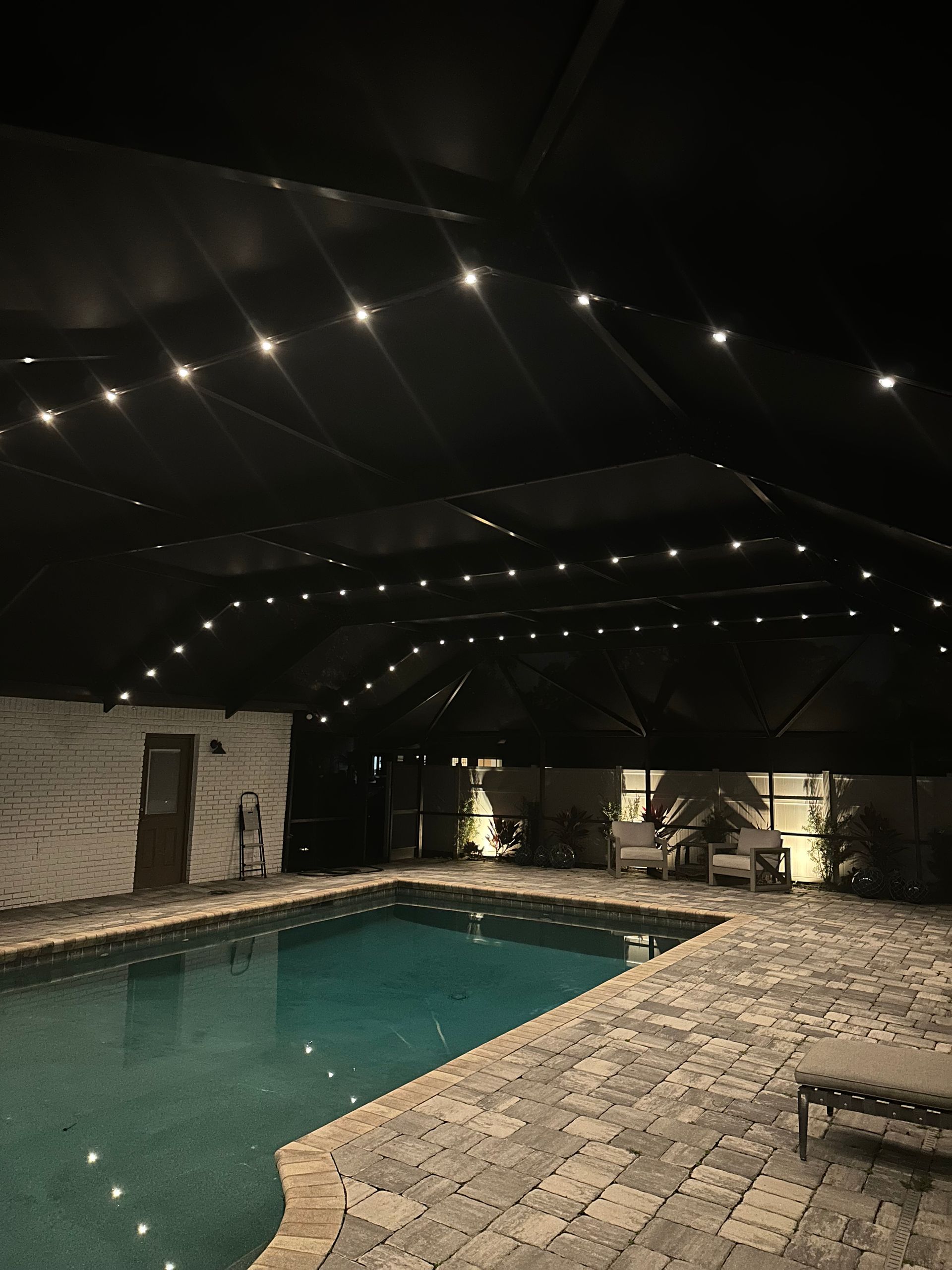 Screened pool enclosure with permanent lighting along the cage frame