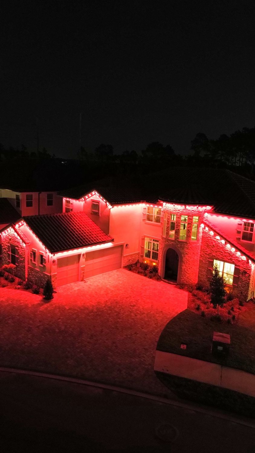 Aerial view of a home with red permanent color-changing roofline lighting